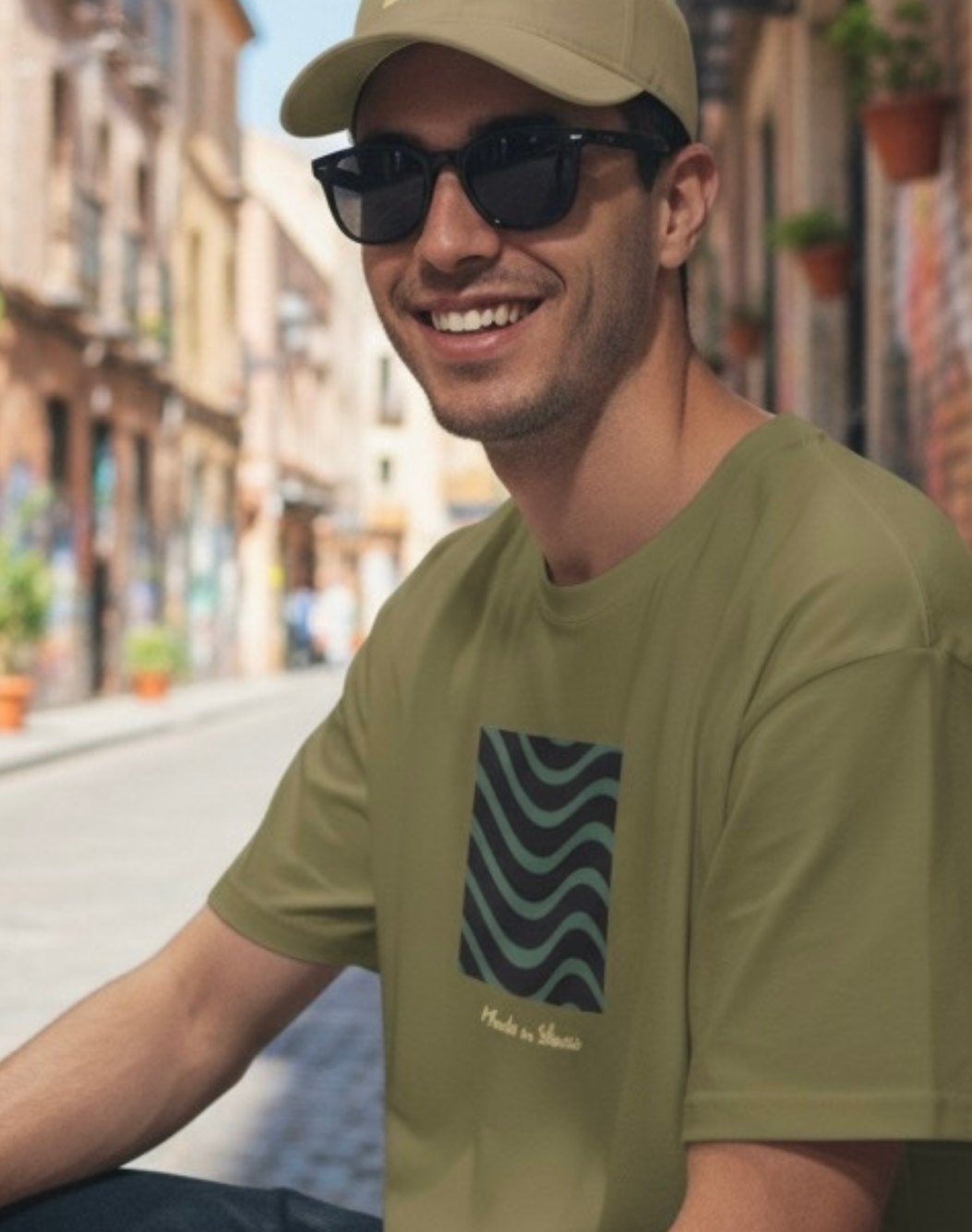 Modelo con la camiseta Wavy Crest oliva y gorra caqui en la calle